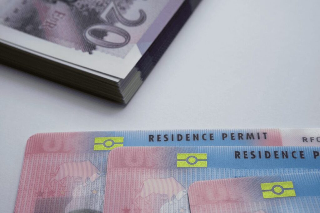 Close-up of residence permit cards with stack of banknotes in background