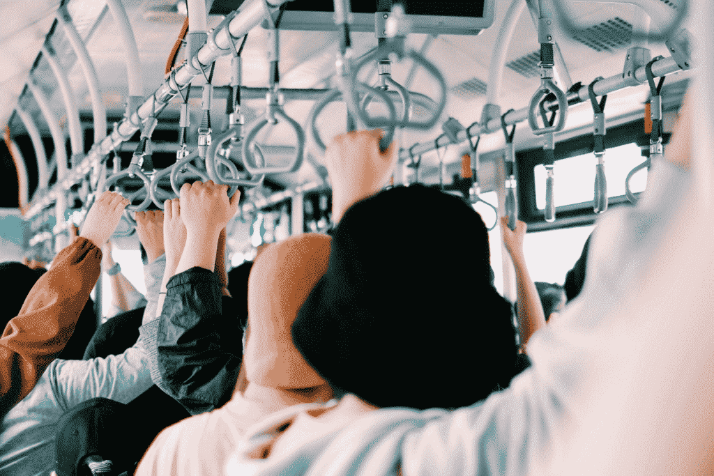 Passengers holding overhead handles on a crowded public transport vehicle