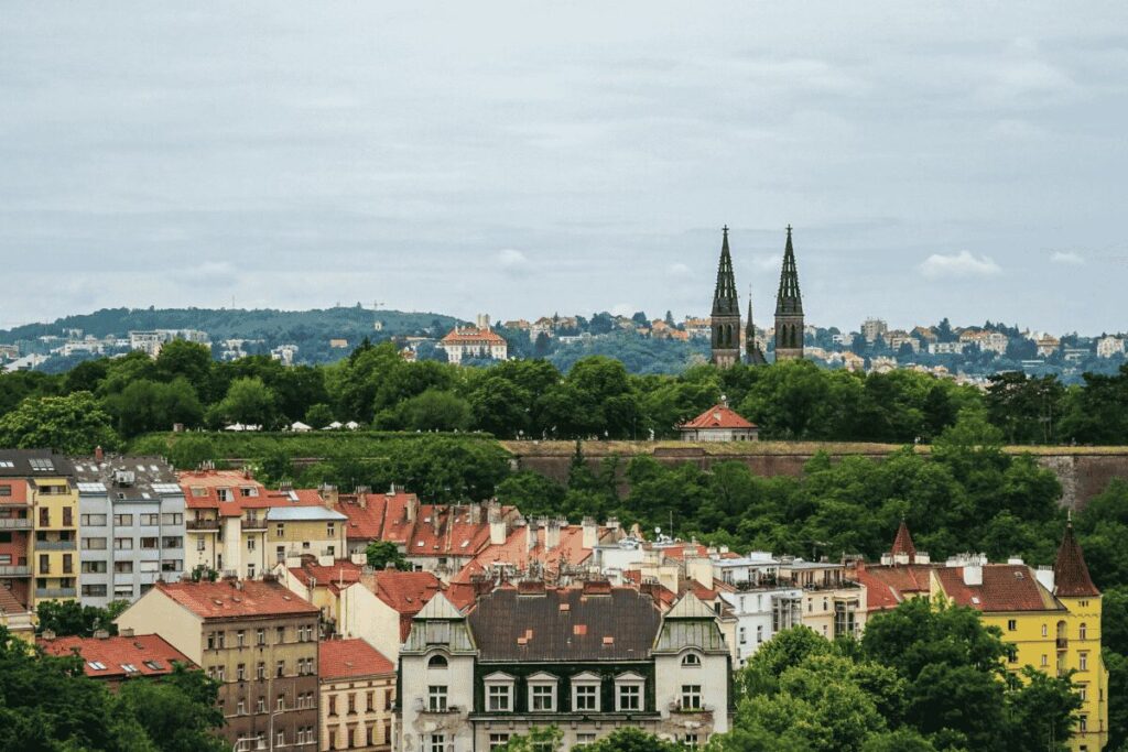 Prague in spring with green hills and red rooftops — shoulder season for affordable hotels in Prague