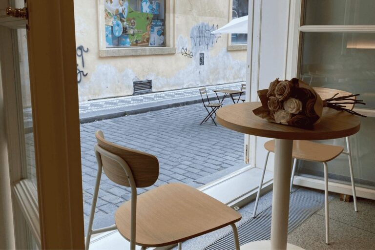 Modern café seating in Prague Old Town with wooden chairs and street view – part of the best cafes in Prague guide