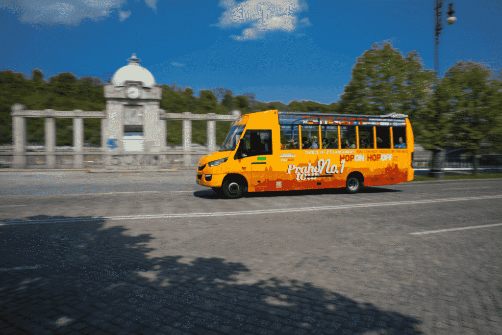 Hop-on hop-off sightseeing bus passing historic architecture in Prague