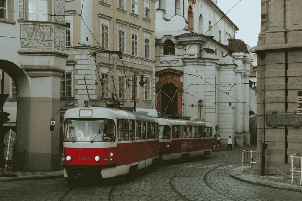 Red tram on Prague street with historic buildings, illustrating Prague public transport system
