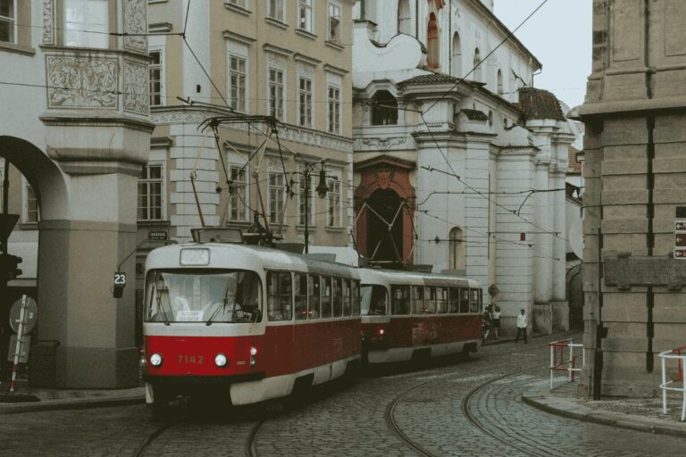 Red tram on Prague street with historic buildings, illustrating Prague public transport system