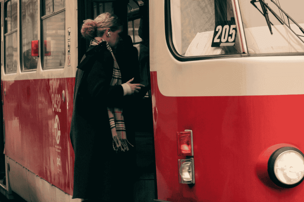Passenger boarding a red and white Prague tram, showing the city's iconic public transport system
