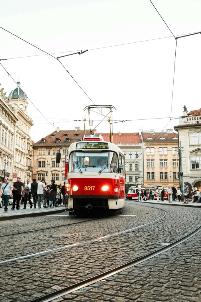 Red Prague tram on cobblestone street with historic buildings in city center