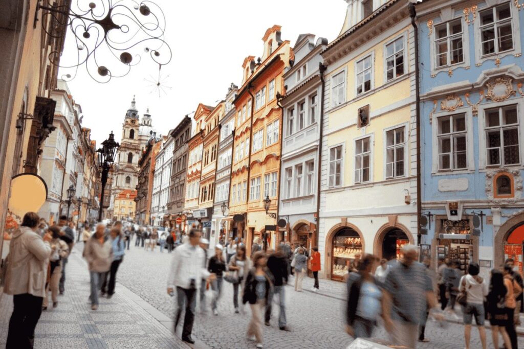 People walking along a cobblestone street in Prague’s Old Town with colorful historic buildings