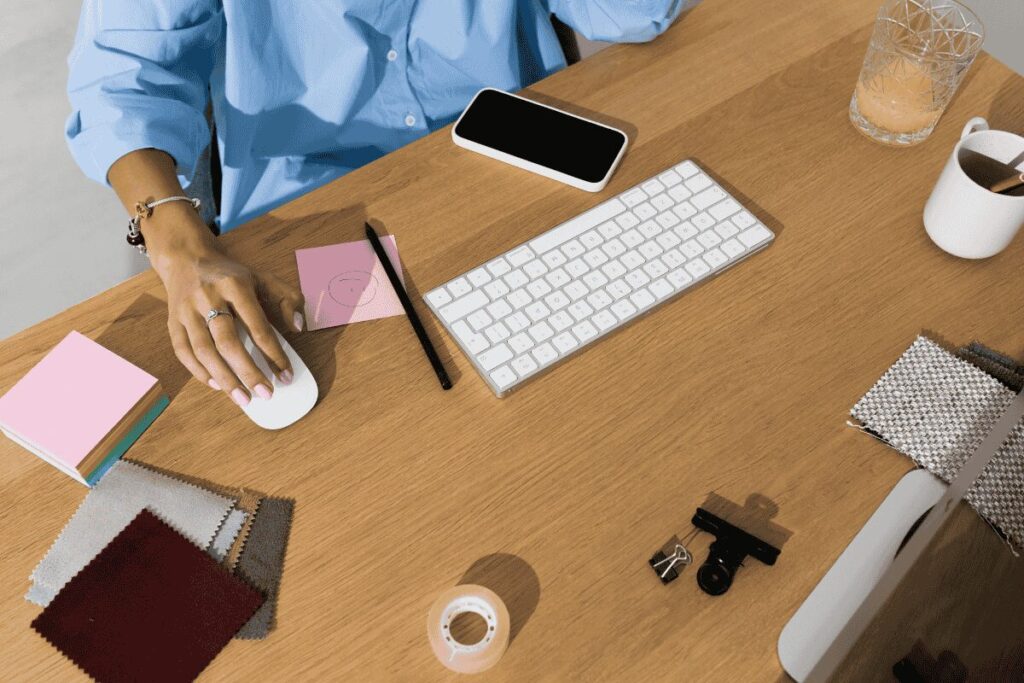 Overhead view of a tidy desk with a keyboard, phone, notebook and coffee — used to illustrate the  preparation process for a Czech visa application