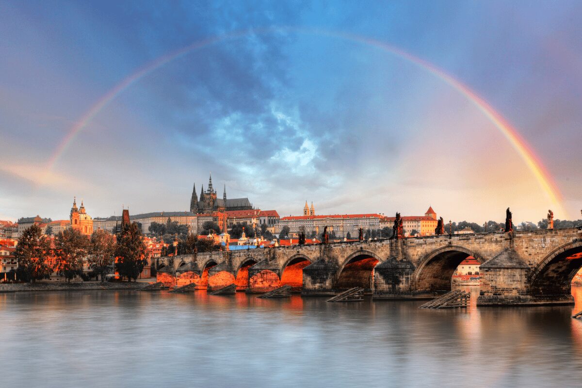 Prague skyline with Charles Bridge and Prague Castle under a rainbow at sunset