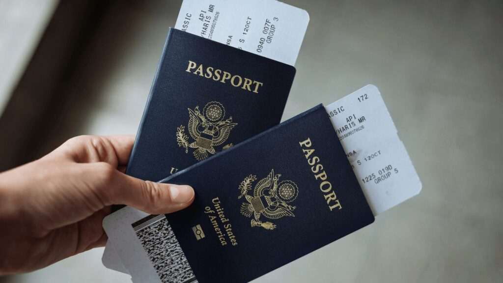 Two U.S. passports with boarding passes held in a hand, representing a travel document required for a Czech student visa application.
