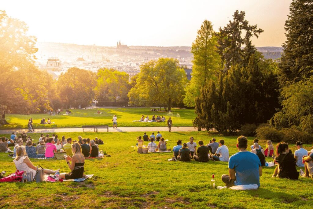 People sitting on the grass at Riegrovy sady during sunset in Prague.