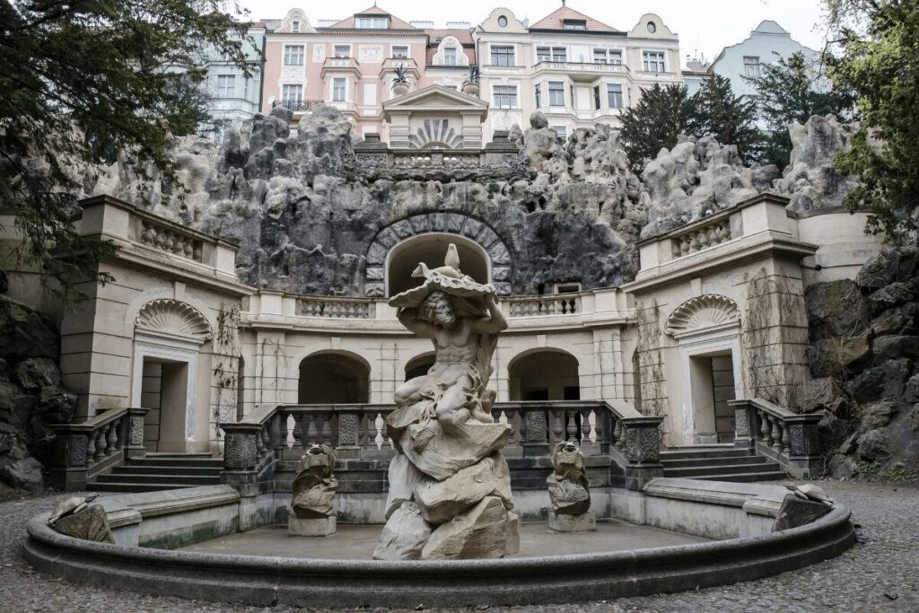 Ornate grotto and fountain at Grébovka (Havlíčkovy sady) garden in Prague, featuring a dramatic cave-like rock structure and statue.