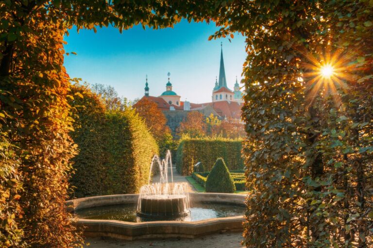 Fountain framed by manicured hedges in Waldstein Garden Prague with sunlight shining over the Baroque garden.