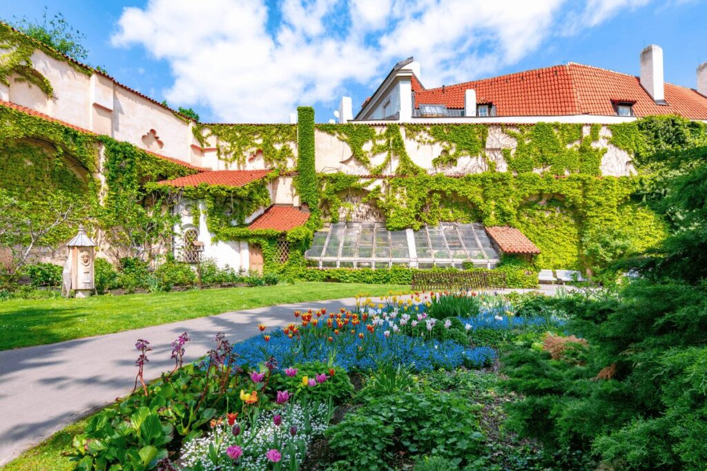 Flower beds and ivy-covered walls inside Vojanovy Gardens, a historic monastery garden in Malá Strana, Prague.