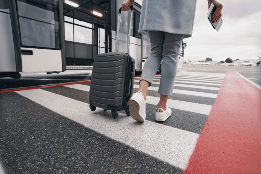 Traveler pulling a suitcase across a crosswalk outside an airport